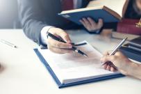Two hands holding pens signing a contract